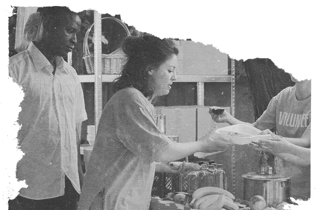 A woman receiving a plate of food from a person wearing a shirt that reads “Volunteer”