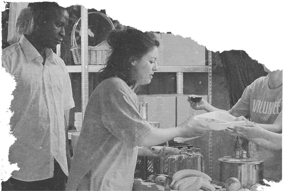A woman receiving a plate of food from a person wearing a shirt that reads “Volunteer”